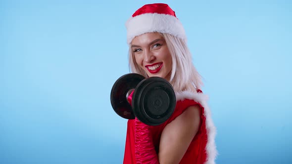 Sexy Young Woman in Santa Claus Costume with Dumbbell