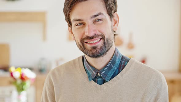 Young Positive Bearded Guy Smiling to Camera Posing at Home Interior with Spring Bouquet Tracking alt