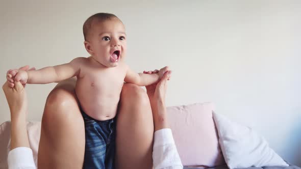 Happy faceless mother playing with baby in bedroom alt