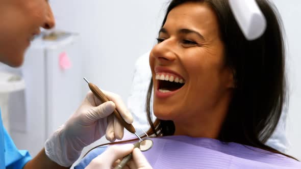 Dentist examining a female patient with tools alt