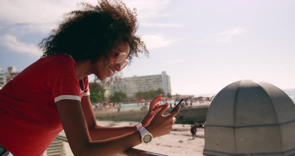 Woman using mobile phone at beach promenade in sunshine 4k