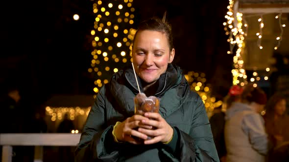 Happy woman holding traditional food at Christmas market. Zagreb, Croatia alt