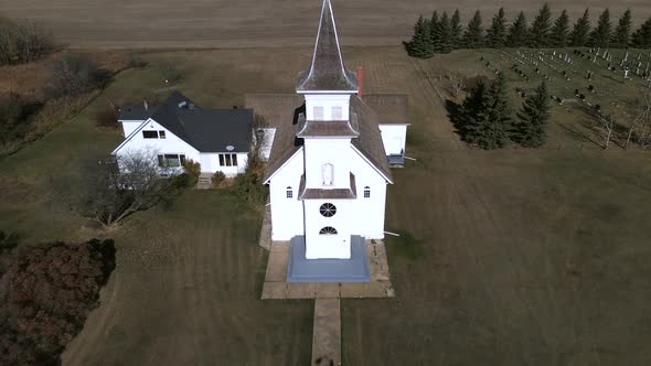 Slow aerial pull backement in 4k revealing beautiful old country church and person walking towards i alt
