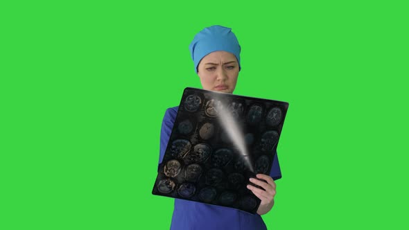 Female Doctor Looking at Brain Tomography on a Green Screen, Chroma Key. alt