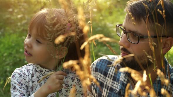 Father with Little Child Play in Ears of Wheat at Sunset in Summer Meadow. Happy Family Concept.