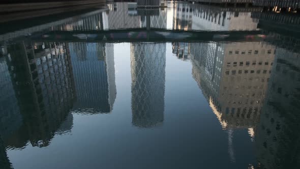 Pan up from Canary Wharf middle dock reflection to Newfoundland tower building alt