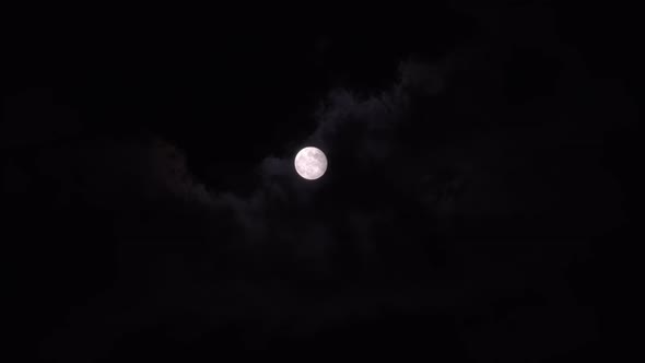Bright Full Moon Behind Fast Moving Dark Clouds on Night Sky alt