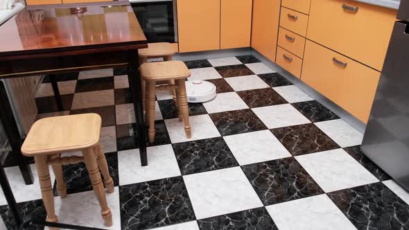 Robot Vacuum Cleaner Cleans in the House at Kitchen alt