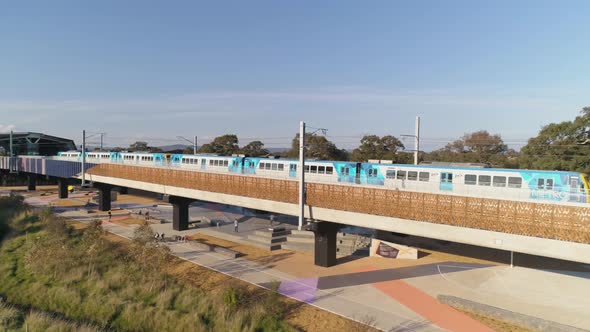 Aerial shot panning from Skatepark underneath train station to train line running overhead alt