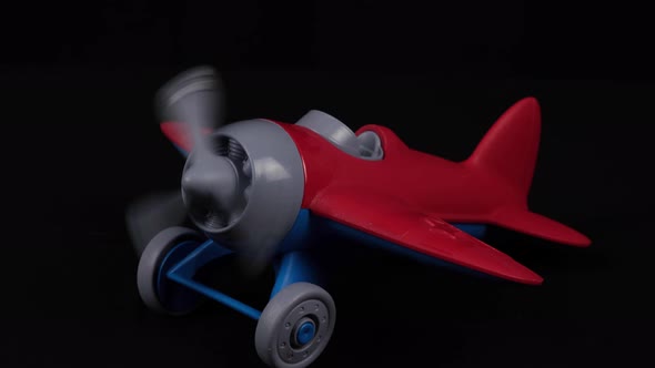 The Propeller Of The Wheeled Toy Airplane Is Spinning in front of the Black Background alt
