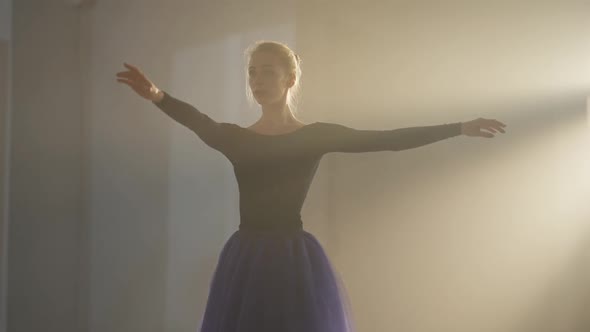 Medium Shot of Graceful Slim Ballerina in Tutu Spinning in Backlit Fog in Second and Fifth Position alt