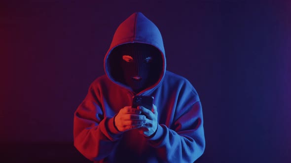 phone scammer in a mask writes a text message