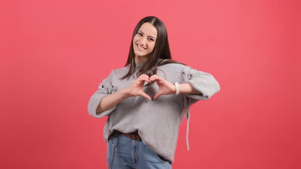 Happy Woman Put Make with Fingers Heart Shape, Isolated Over Red Background alt