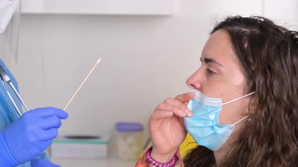 Nurse in a Protective Suit Takes a Nasal Swab Sample From a Young Female Patient