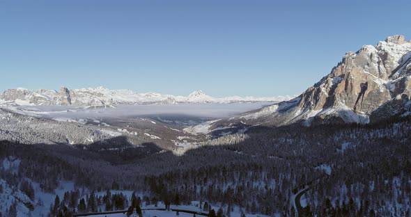 Forward Aerial to Snowy Valley with Woods Forest and Road at Valparola Pass alt