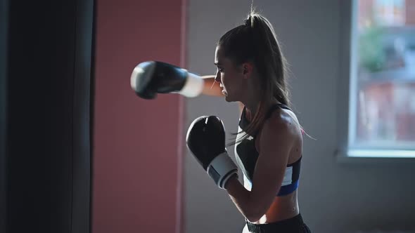 Slow Motion of a Girl Preparing for a Boxing Competition and Trains Punches on a Punching Bag in a alt