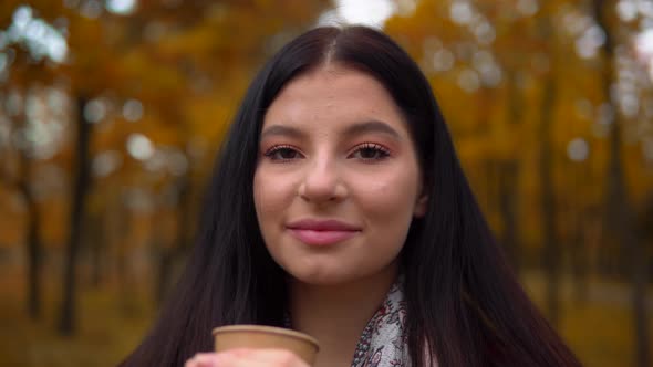 Woman Looking at Camera Drinking Hot Coffee Tea Outdoor Autumn Walking at Park