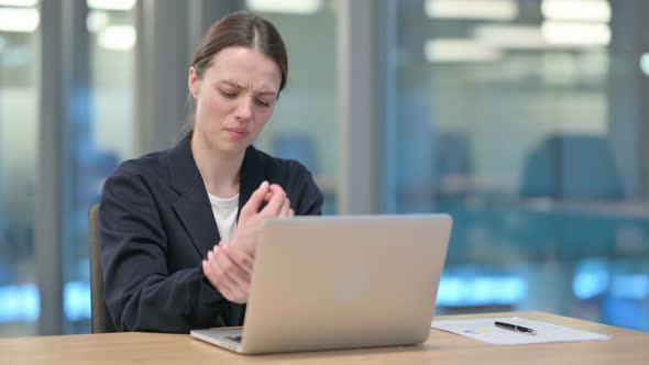 Young Businesswoman having Wrist Pain while Typing on Laptop alt