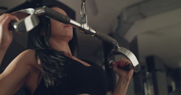 Female Athlete Works Out with the Simulator to Pump Chest's' Muscles in Gym alt