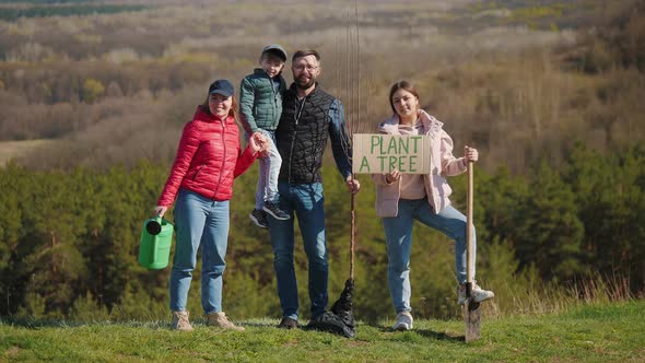 Portrait of a Family of Volunteers with Children Before Planting a Tree in Nature alt