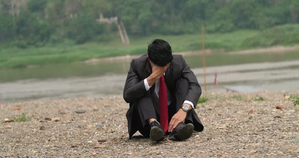 Businessman Sitting And Depressed Near River alt
