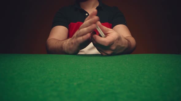 Male Hands Shuffle a Deck of Playing Cards Above Poker Table