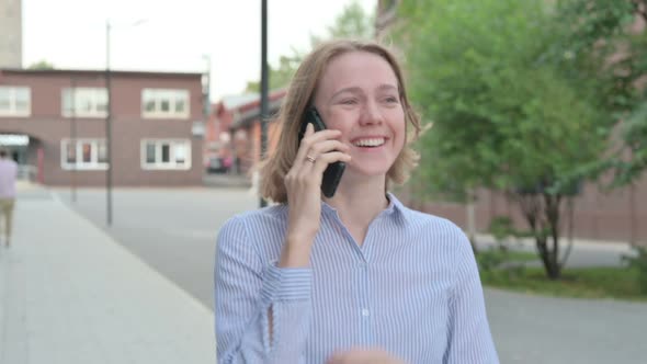 Woman Talking on Phone While Walking in Street alt