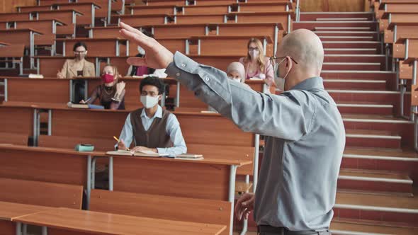 Male Professor and Group of Students in Face Masks Having Lesson alt