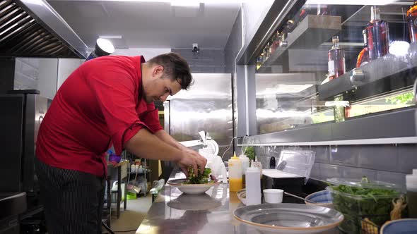 Cook in Restaurant Kitchen Preparing an Avocado Salad alt
