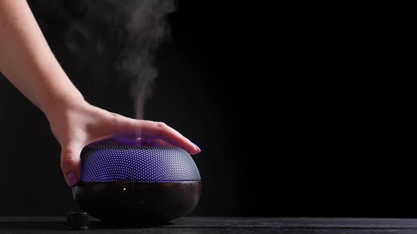 Woman Add Essential Oil Into Diffuser on Black Wooden Table alt