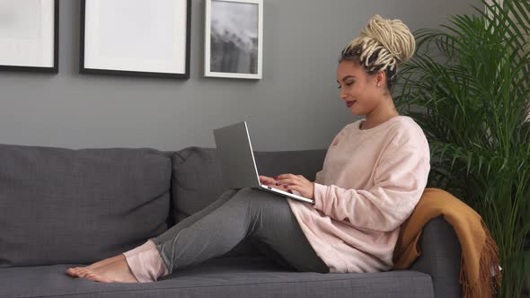 Young Beautiful Woman Working on Laptop and Smiling on Comfortable Sofa at Home alt