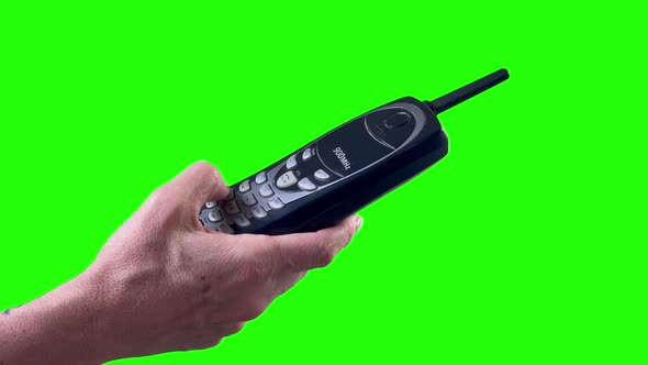 Hand Holding Old Cordless Phone on a Green Background. 4K.