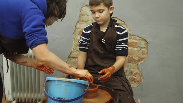 Closeup of Adult and Child's Dirty Hands Molding Clay Into Ceramic Pot