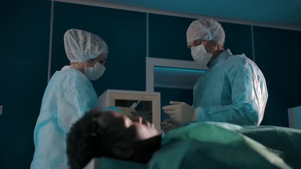 Professional Surgeons Adult Male and Young Woman Prepare Tools for Surgery alt