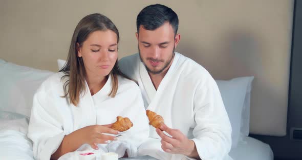 Lovely Couple Eats Croissants Having Breakfast on Large Bed