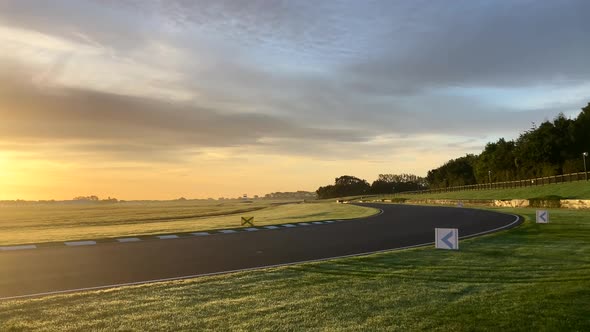 Camera panning left as the sun rises over an empty Goodwood race track alt