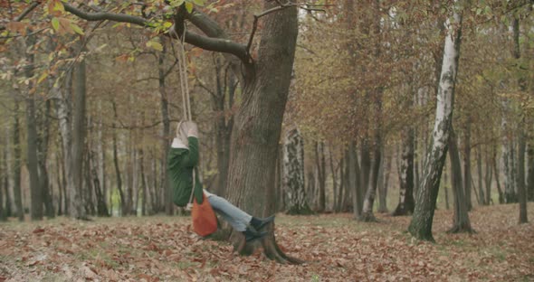Side View of a Young Woman Swinging Under an Old Tree in Autumn. Slow Motion alt