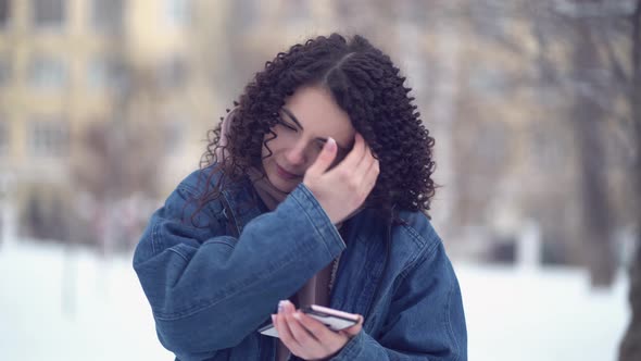 Young Beautiful Curly Woman in Winter Clothes Using Phone at Winter