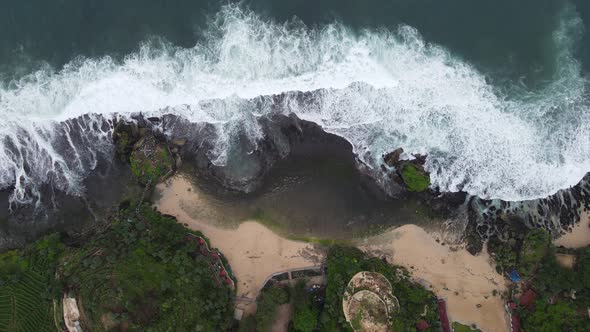 Top down aerial view of giant ocean waves crashing and foaming in coral beach alt