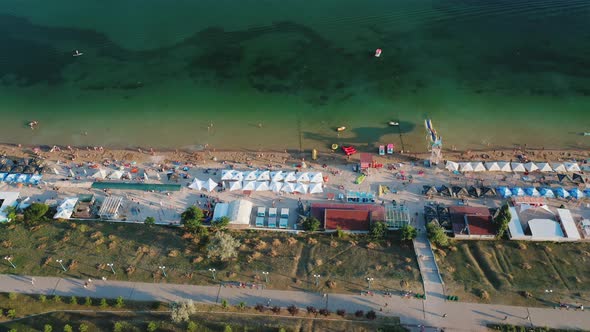Aerial View of People Resting on a Summer City Beach in the Evening alt