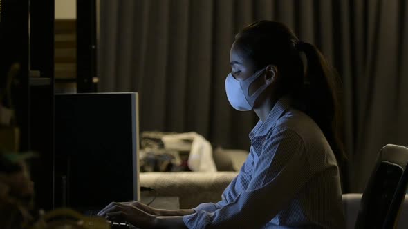 Woman Wearing Face Mask to Protect From Coronavirus Covid19 While Working at Home Late at Night