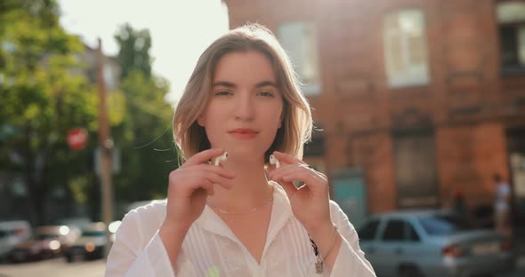 Woman Wearing Wireless Earbuds in a Summer City Slow Motion alt