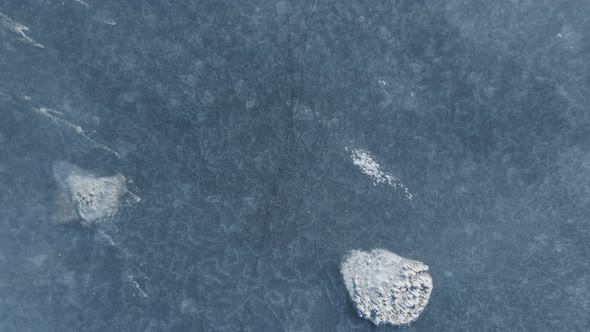 Shot From Close to Aerial of Blue Frozen Lake with Cracks and Bubbles
