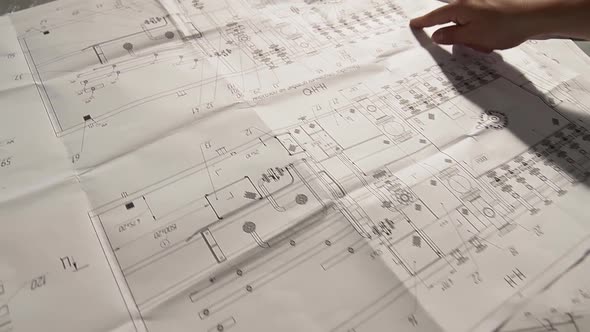 Blueprints of Oil and Gas Equipment Drawings. Fingers of a Human Being Show Circuit on Printed alt