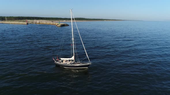 Aerial view of beautiful sailboat sailing out into the calm sea after sunrise. Baltic sea