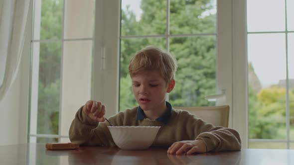 Unsatisfied 6 Years Old Boy Eating Meal Sitting Alone at Home alt