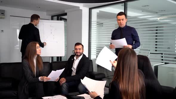 Smiling Millennial Male Coach or Presenter Make Flip Chart Presentation Ask Question During Work