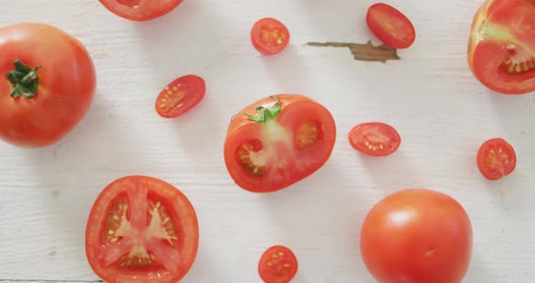 Video of fresh halved and whole red tomatoes on white rustic background alt