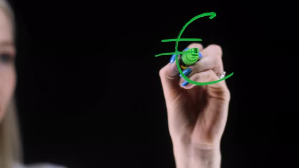A Woman's Hand Draws the Euro Sign on a Transparent Board alt