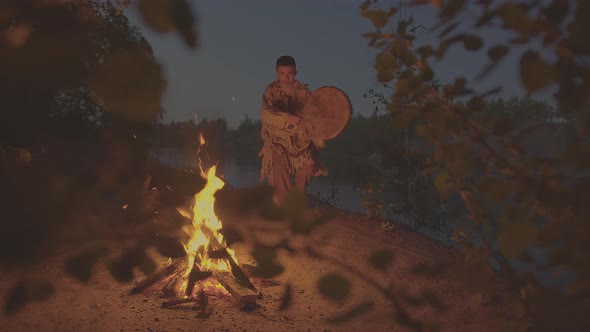 A Shaman with a Drum Jumps in Around the Fire in Clothes for the Ceremony